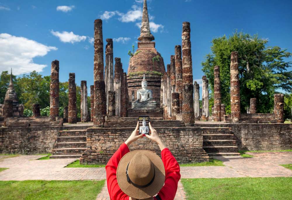 Touriste féminin prenant des photos de Wat Sa Si à Sukhothai